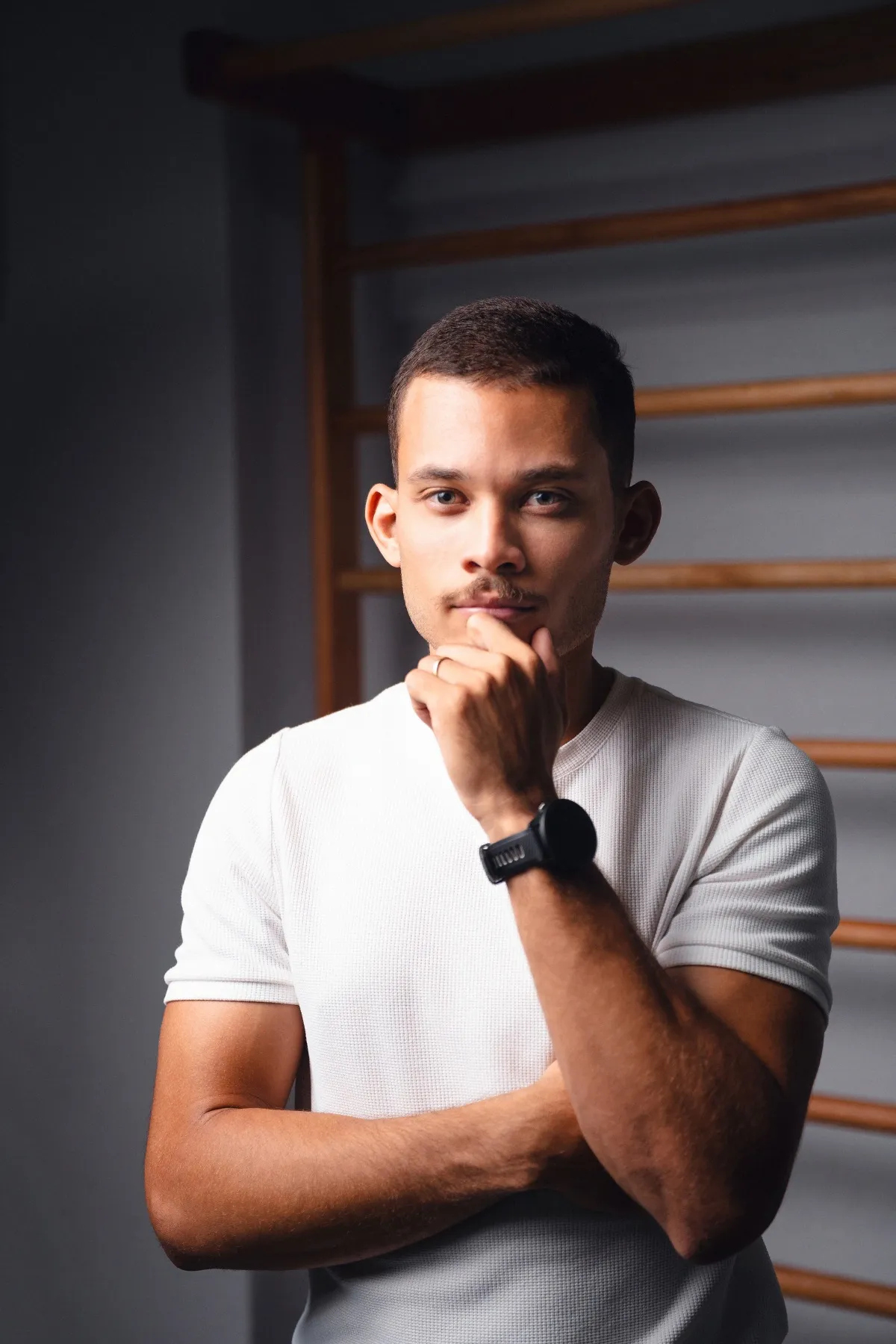 Marlon Torres de camiseta branca, com a mão no queixo, em pose pensativa