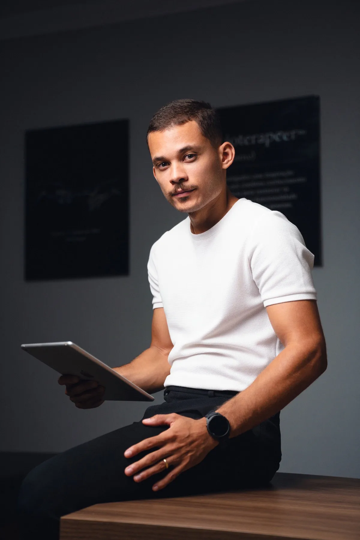 Marlon Torres de camiseta branca, sentado com um tablet na mão