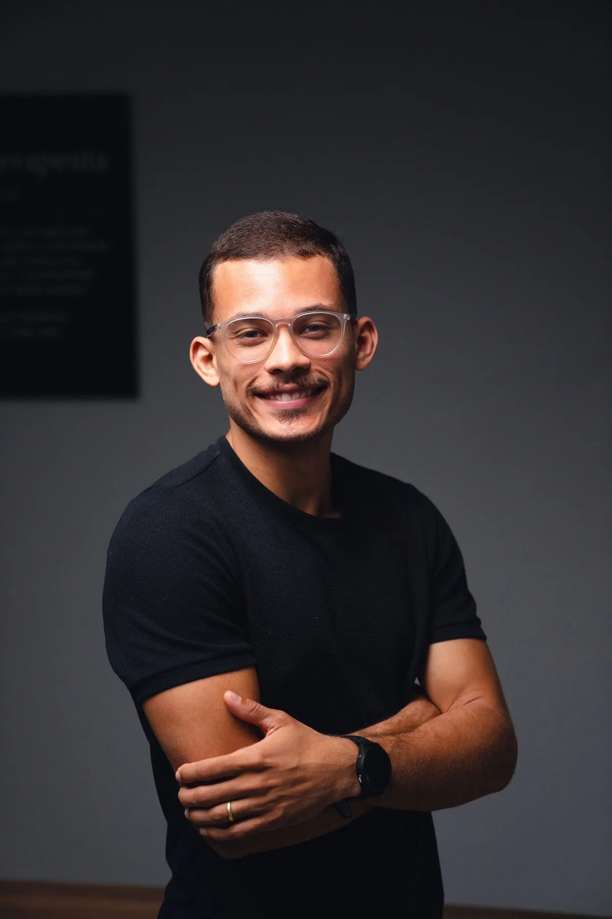 Marlon Torres de camiseta preta e braços cruzados, sorrindo