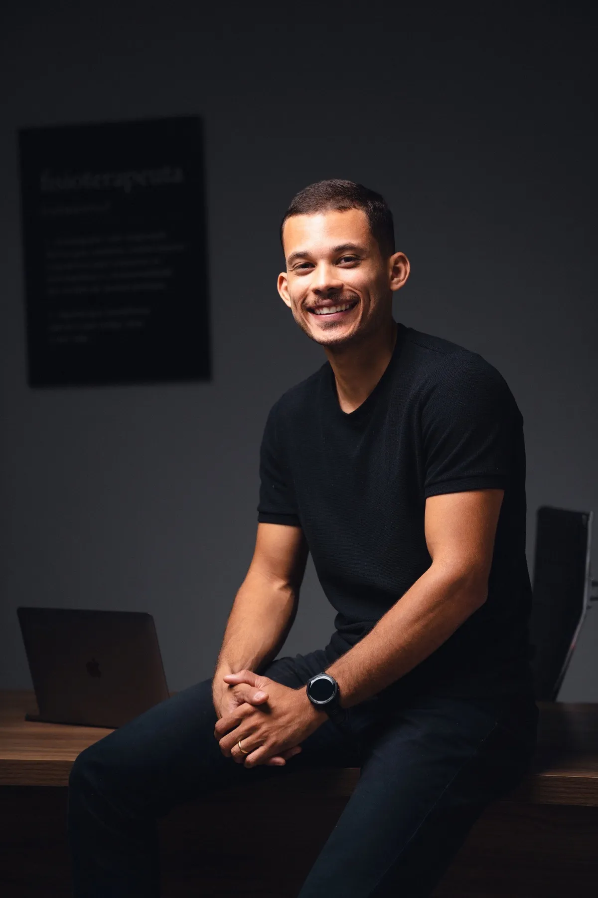 Marlon Torres sorrindo, sentado na beira da mesa do consultório