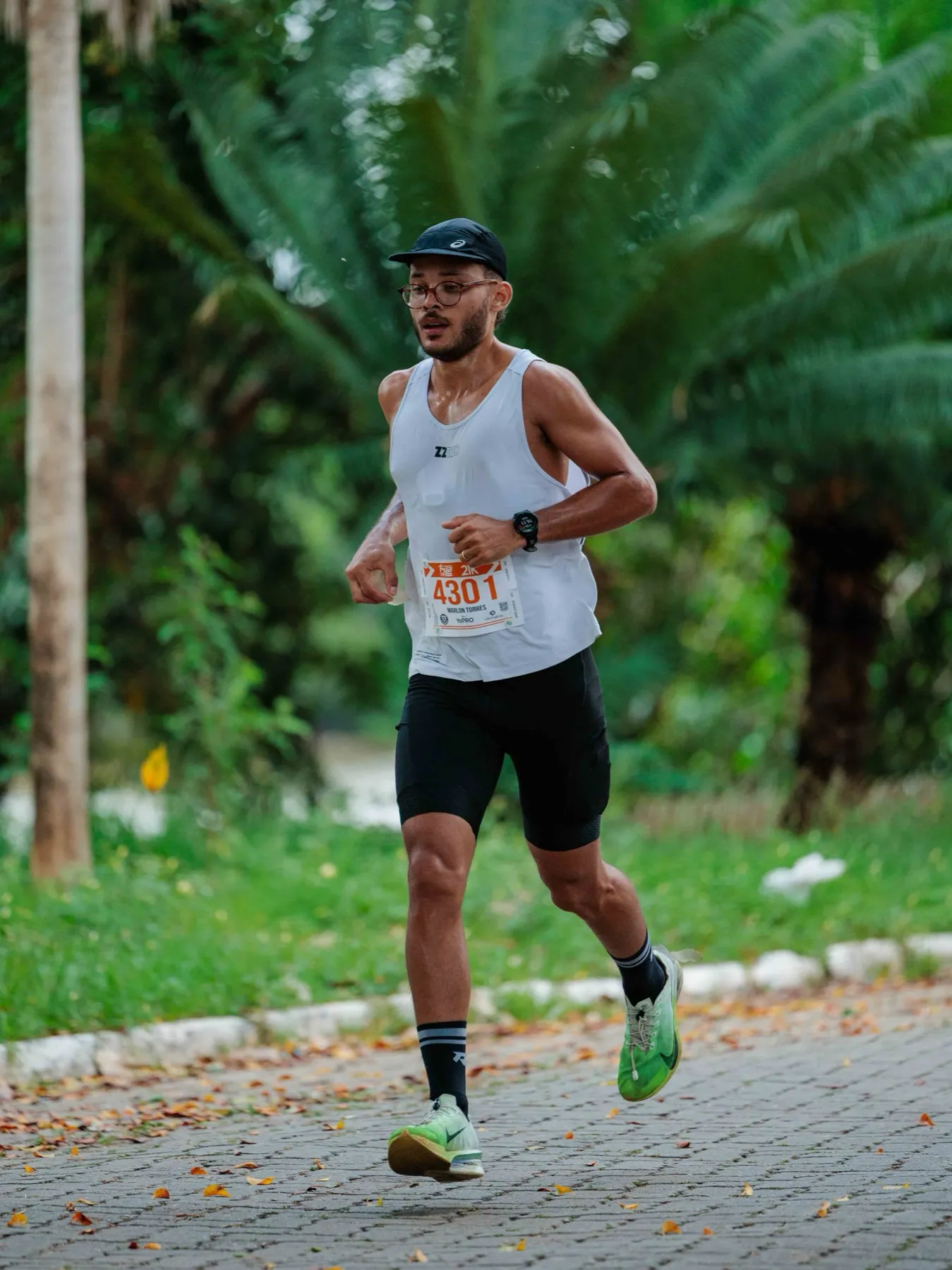 Marlon Torres correndo numa prova de rua, de boné, regata branca e número de peito