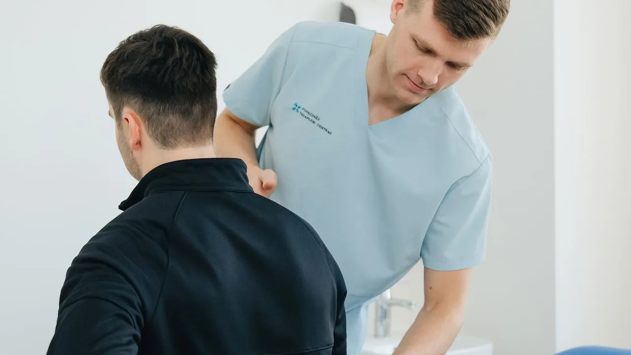 Fisioterapeuta avaliando a coluna de um paciente no consultório.